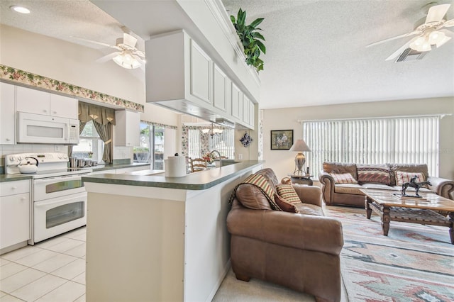 kitchen featuring kitchen peninsula, white appliances, a textured ceiling, and white cabinets