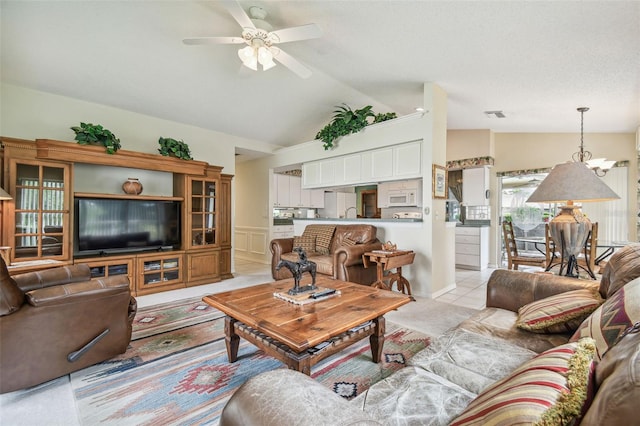 tiled living room with lofted ceiling and ceiling fan with notable chandelier