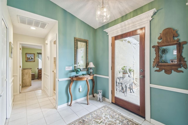 tiled entrance foyer featuring a chandelier and a textured ceiling