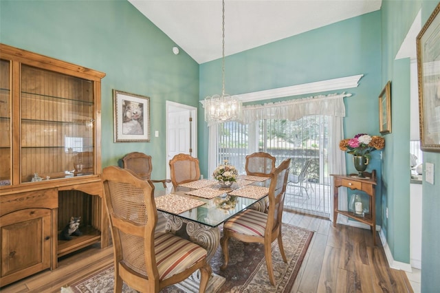 dining room with high vaulted ceiling, hardwood / wood-style flooring, and a chandelier