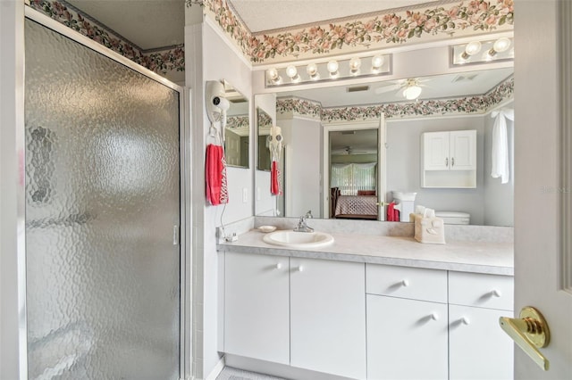 bathroom with ceiling fan, a shower with shower door, and vanity