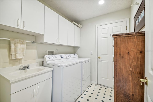 washroom featuring washing machine and dryer, cabinets, sink, and a textured ceiling