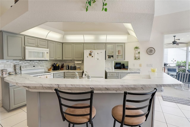 kitchen with a kitchen breakfast bar, white appliances, kitchen peninsula, a textured ceiling, and ceiling fan