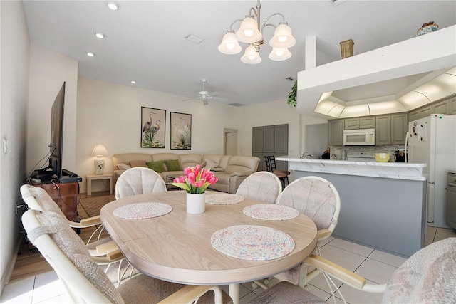 tiled dining room featuring ceiling fan with notable chandelier