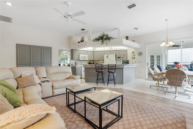 living room featuring ceiling fan with notable chandelier and light hardwood / wood-style flooring