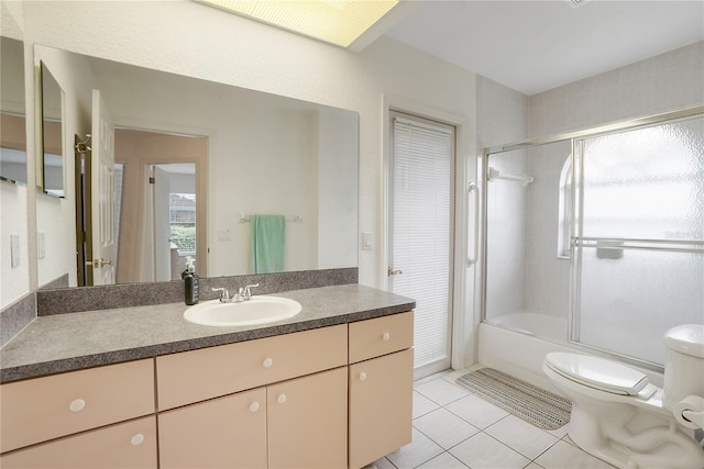 full bathroom featuring tile patterned flooring, vanity, toilet, and bath / shower combo with glass door