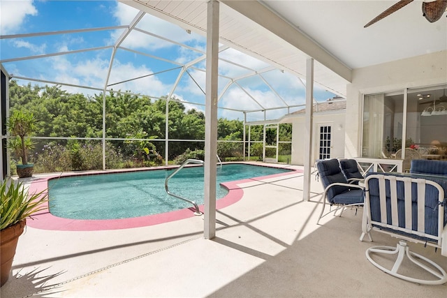 view of swimming pool with glass enclosure, ceiling fan, and a patio