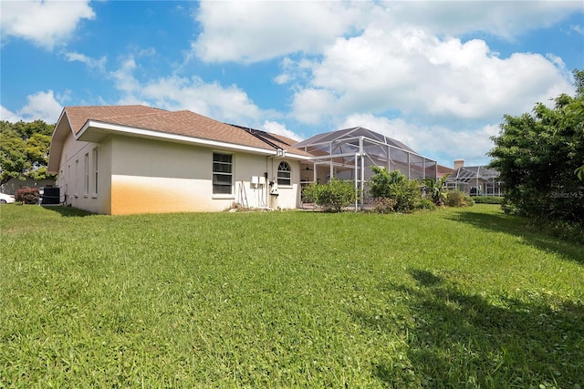 back of property with a lawn, a lanai, and central air condition unit