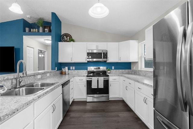 kitchen with pendant lighting, appliances with stainless steel finishes, vaulted ceiling, and white cabinetry