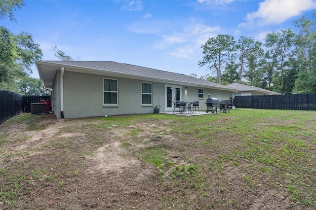 rear view of house with a patio, a yard, and central AC