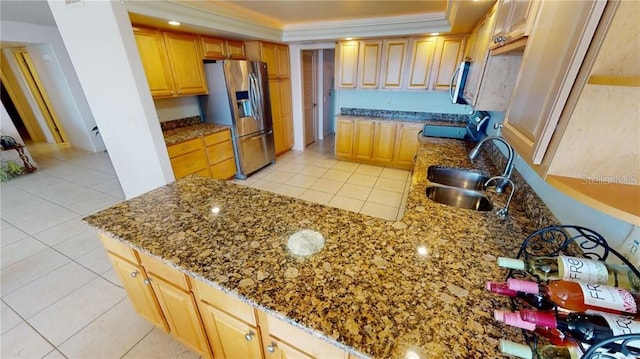 kitchen with light tile patterned flooring, stainless steel appliances, stone counters, and sink