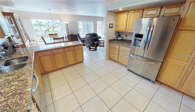 kitchen with pendant lighting, light tile patterned flooring, sink, stone counters, and stainless steel fridge