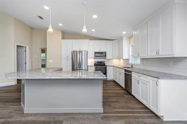 kitchen featuring white cabinetry, appliances with stainless steel finishes, decorative light fixtures, dark wood-type flooring, and a center island