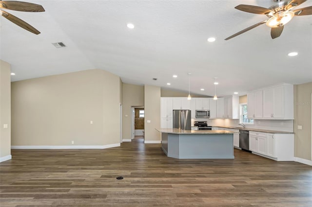 kitchen featuring appliances with stainless steel finishes, a kitchen island, dark hardwood / wood-style flooring, white cabinets, and vaulted ceiling