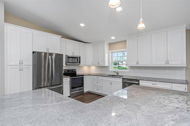 kitchen featuring stainless steel appliances, light stone countertops, white cabinetry, and pendant lighting