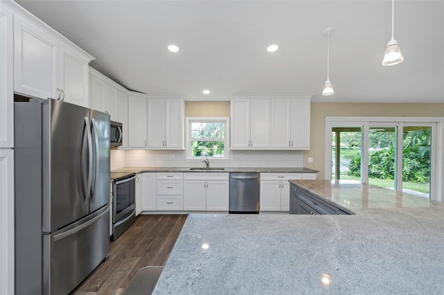 kitchen with light stone countertops, stainless steel appliances, dark hardwood / wood-style floors, and plenty of natural light