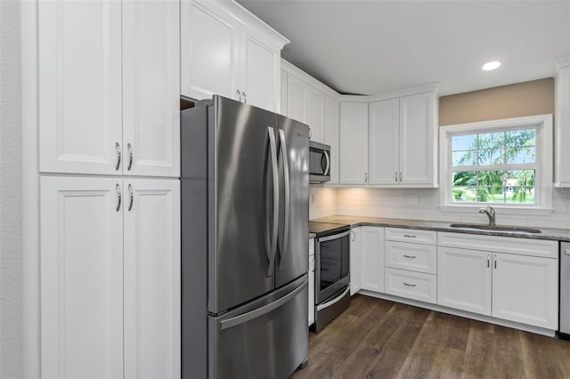 kitchen with white cabinetry, sink, appliances with stainless steel finishes, dark hardwood / wood-style floors, and decorative backsplash