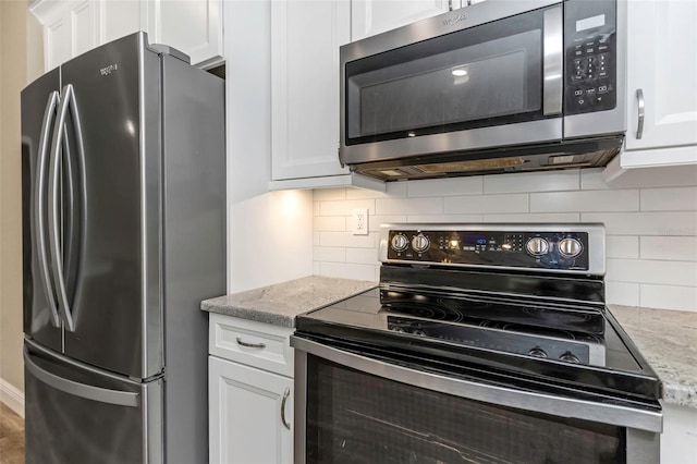 kitchen featuring light stone counters, white cabinetry, appliances with stainless steel finishes, and backsplash