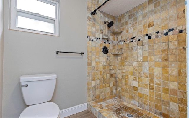 bathroom featuring toilet and a tile shower