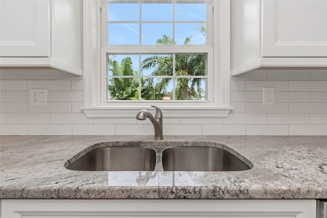 details featuring white cabinetry, sink, light stone counters, and decorative backsplash