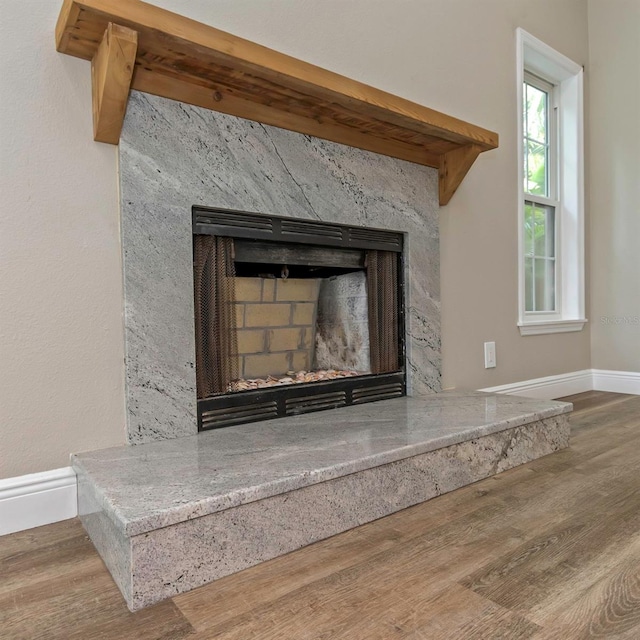 details featuring beamed ceiling, a premium fireplace, and wood-type flooring