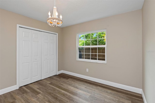 unfurnished bedroom featuring a closet, a chandelier, hardwood / wood-style floors, and a textured ceiling