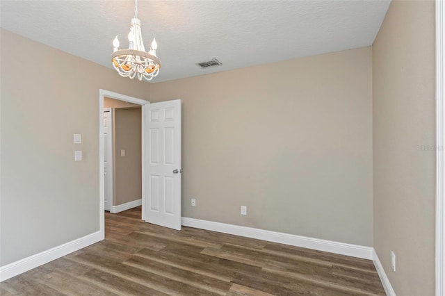 unfurnished room featuring a chandelier, a textured ceiling, and dark hardwood / wood-style flooring