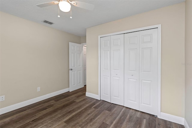 unfurnished bedroom featuring a textured ceiling, ceiling fan, dark hardwood / wood-style floors, and a closet