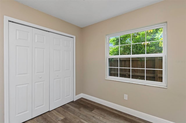 unfurnished bedroom with dark hardwood / wood-style floors and a closet