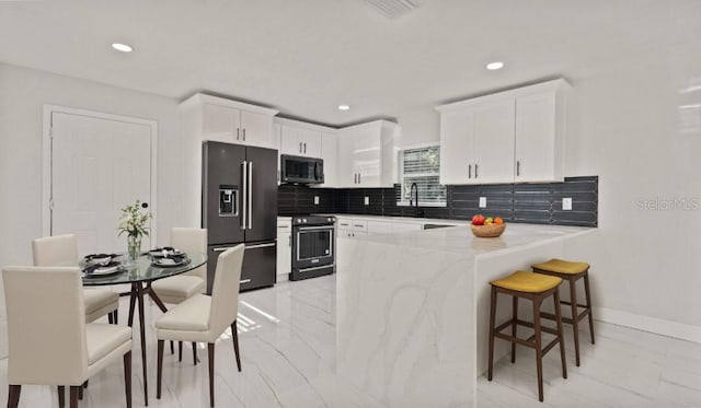 kitchen featuring light stone countertops, appliances with stainless steel finishes, tasteful backsplash, and white cabinetry