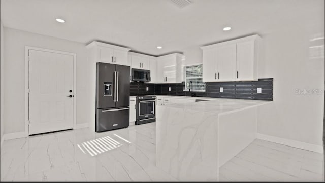 kitchen with light stone counters, kitchen peninsula, tasteful backsplash, white cabinetry, and appliances with stainless steel finishes