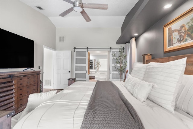 bedroom with a barn door, lofted ceiling, ceiling fan, and hardwood / wood-style flooring