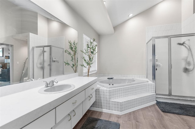 bathroom featuring hardwood / wood-style floors, independent shower and bath, vanity, and vaulted ceiling