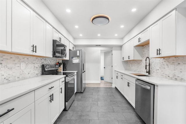 kitchen featuring sink, white cabinetry, decorative backsplash, appliances with stainless steel finishes, and light stone countertops