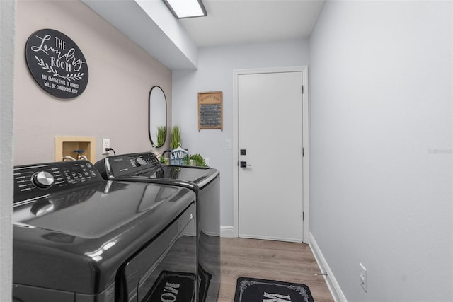 clothes washing area with hardwood / wood-style floors and washing machine and clothes dryer