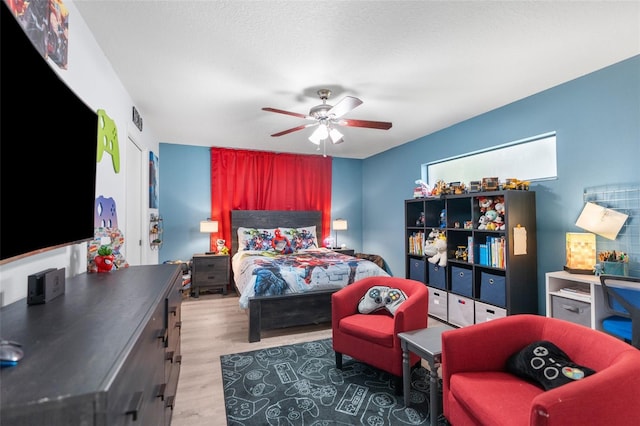 bedroom with ceiling fan, a textured ceiling, and hardwood / wood-style floors