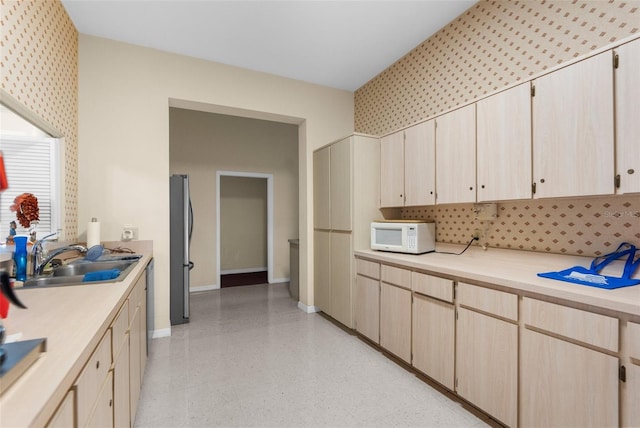 kitchen featuring stainless steel fridge, light brown cabinetry, and sink