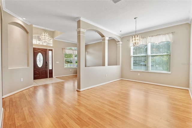 entrance foyer with decorative columns, crown molding, and light wood-type flooring