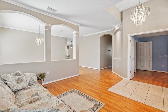 living area featuring arched walkways, visible vents, a chandelier, ornate columns, and wood finished floors