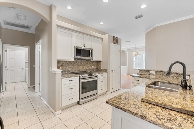 kitchen with sink, backsplash, stainless steel appliances, white cabinets, and light stone counters