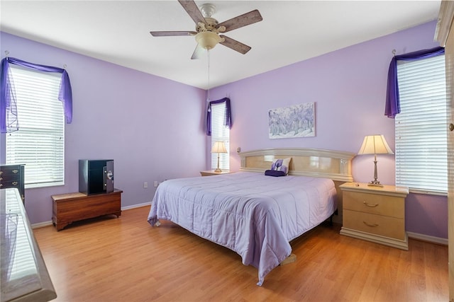 bedroom featuring light wood-type flooring, baseboards, and multiple windows
