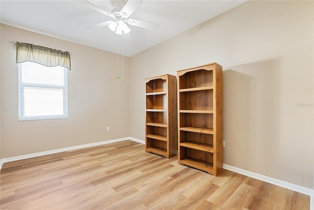 spare room featuring light wood finished floors, baseboards, and ceiling fan