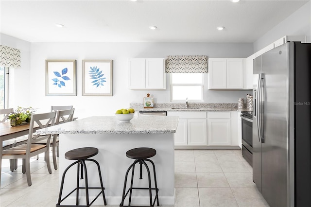 kitchen with light stone countertops, stainless steel appliances, and white cabinets