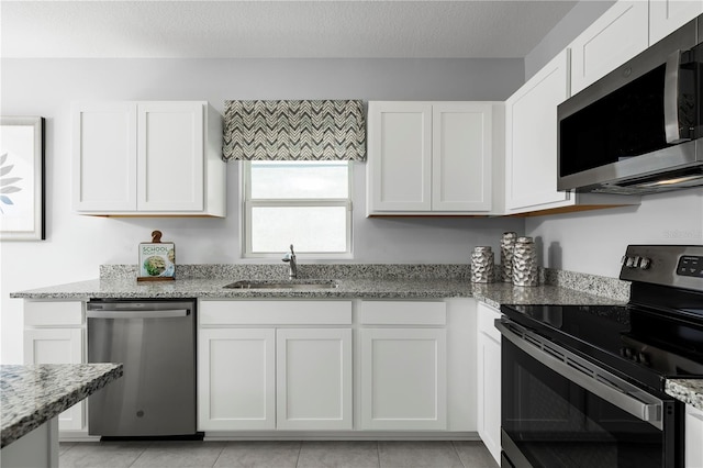 kitchen with light stone counters, sink, stainless steel appliances, and white cabinets