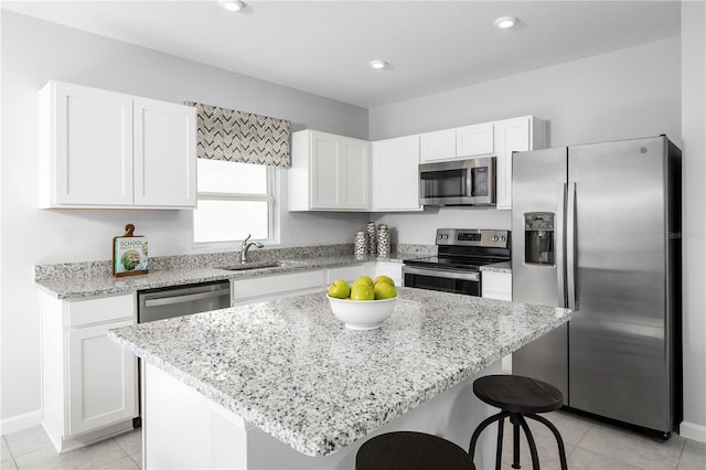 kitchen featuring sink, white cabinetry, appliances with stainless steel finishes, a center island, and a breakfast bar area