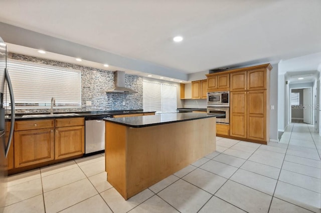 kitchen featuring a center island, sink, wall chimney range hood, backsplash, and appliances with stainless steel finishes