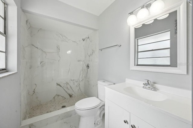 bathroom featuring vanity, toilet, and a tile shower