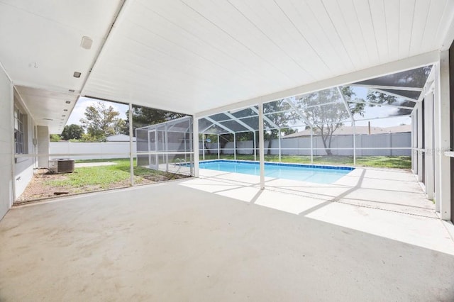 view of pool with central AC unit, glass enclosure, and a patio area