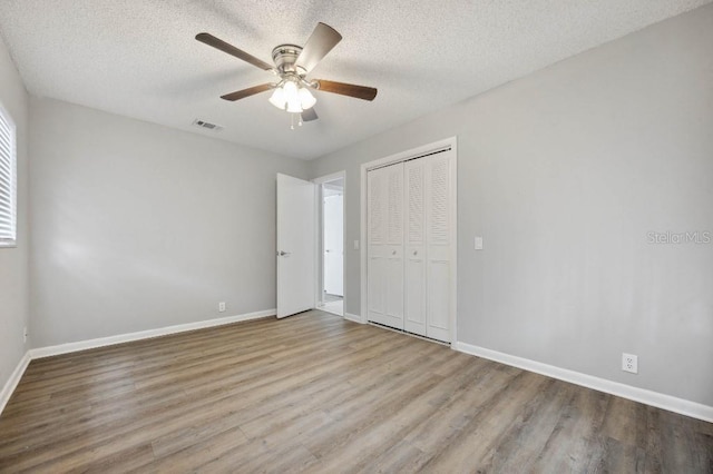 unfurnished bedroom featuring ceiling fan, a textured ceiling, a closet, and light hardwood / wood-style flooring