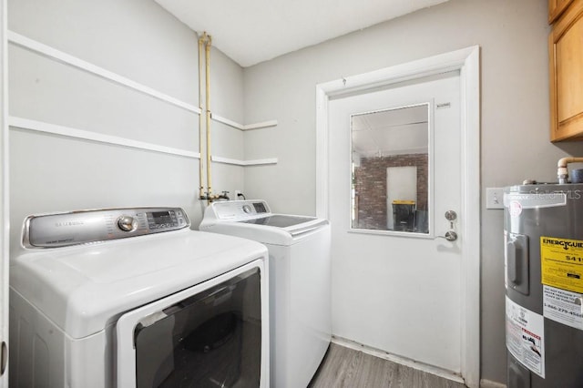 laundry room featuring water heater, cabinets, light hardwood / wood-style flooring, and washer and dryer